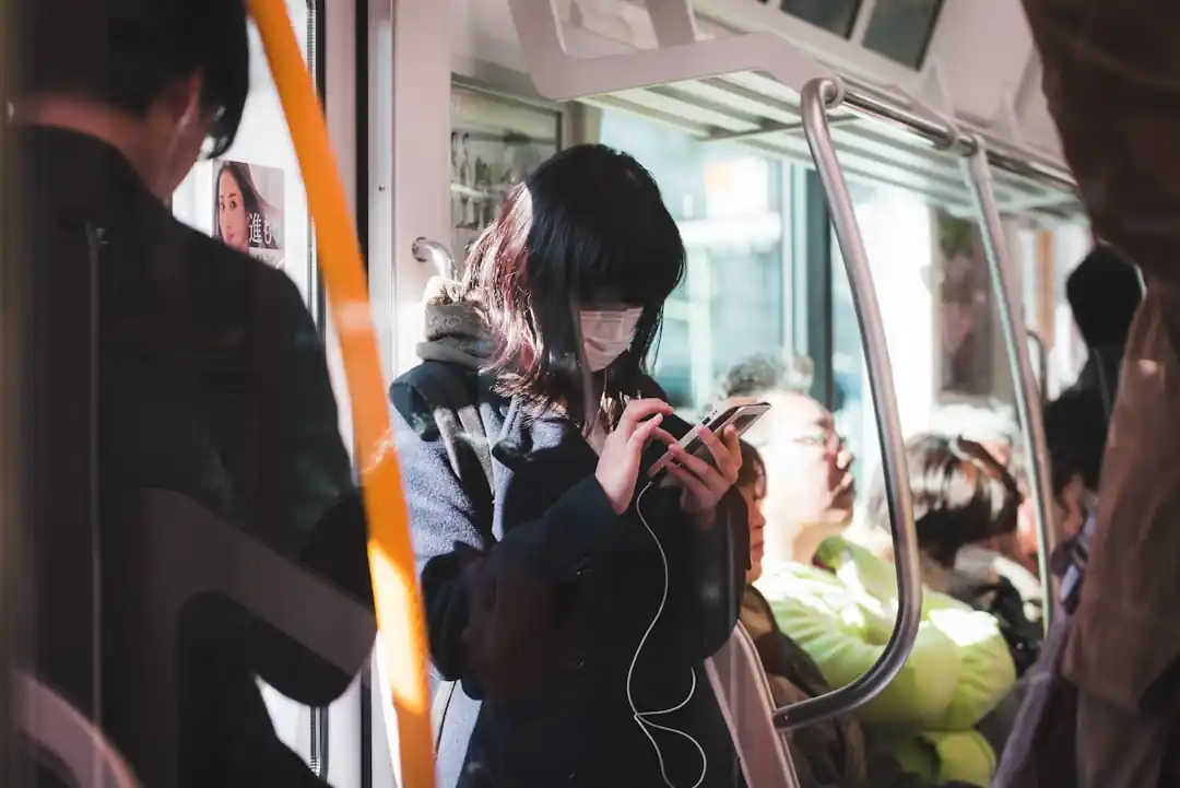 夜の街でスマートフォンを操作しながら音楽を聴いている女性