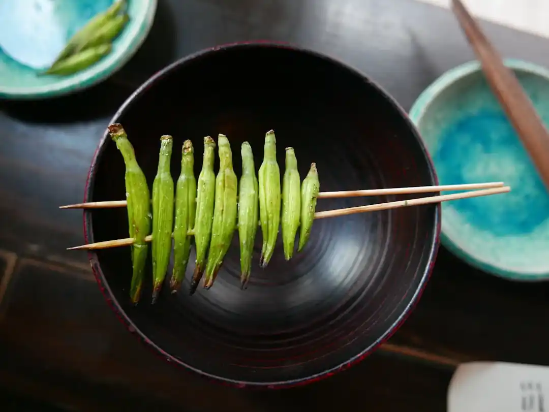 木製の串に刺さった緑色のししとうの焼き物