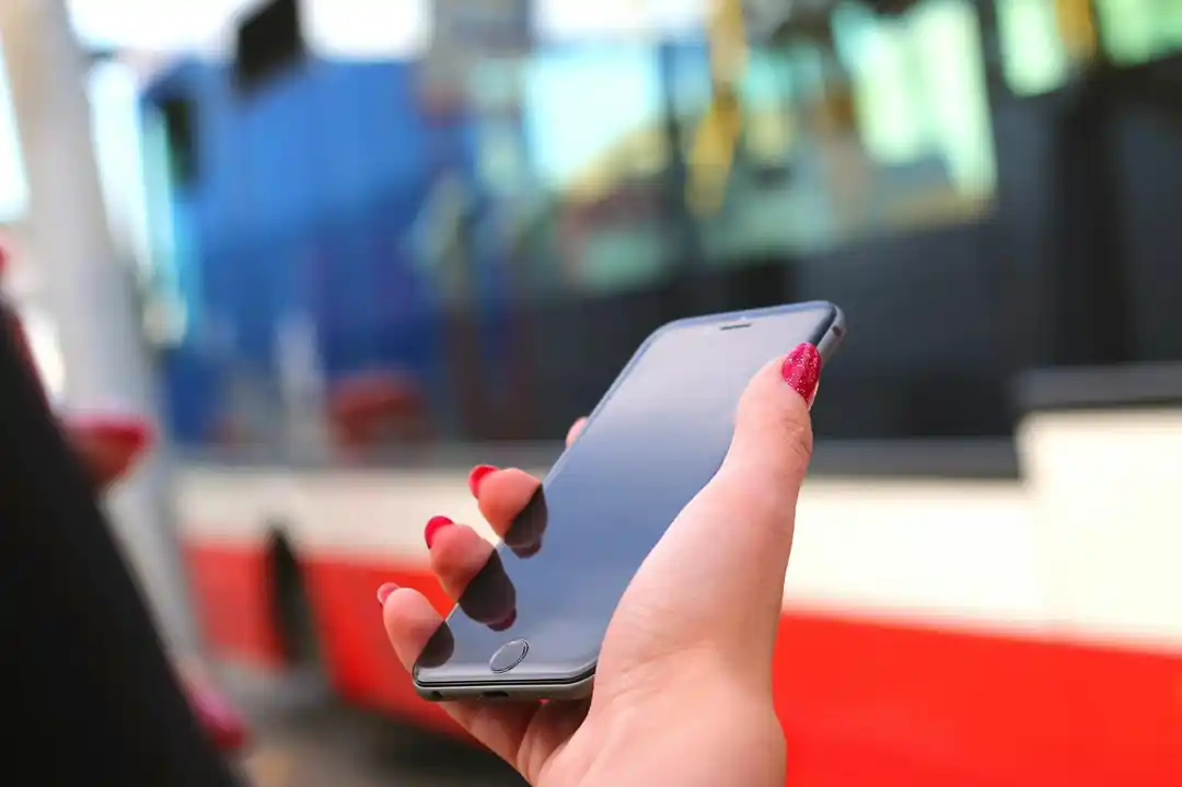一隻手在公車站拿著手機,螢幕上顯示著地圖或APP介面。