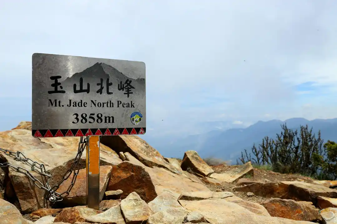 玉山北峰的海拔標示牌,牌上寫著海拔3858公尺,背景是壯闊的山景。