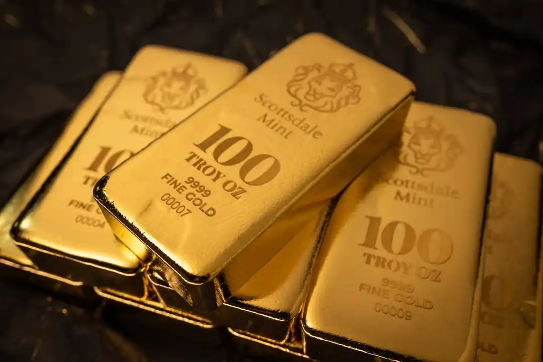 數條100盎司的金條堆疊在深色背景上,光澤溫潤。