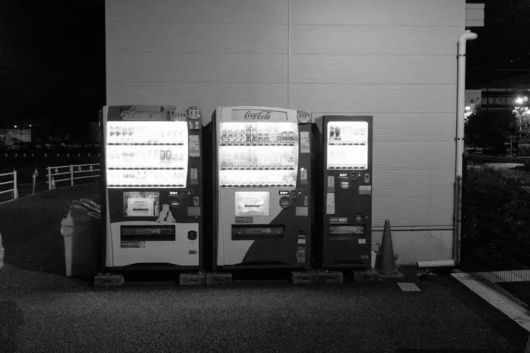 夜の屋外に設置された2台の自動販売機が明るく光っている。