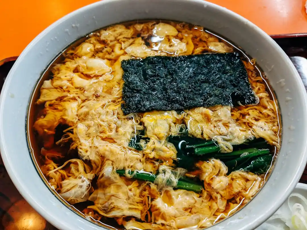 여러가지 고명이 올라간 떡국이 나무 식탁 위에 놓여있다.