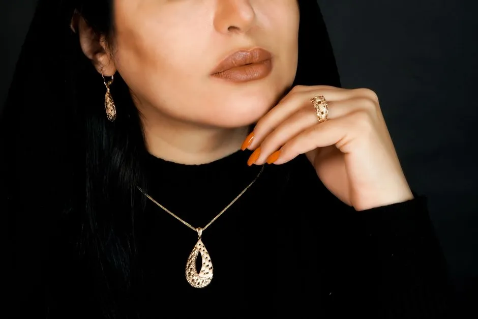 A close-up of a woman wearing an elegant gold jewelry set including a necklace, earrings, and a ring.