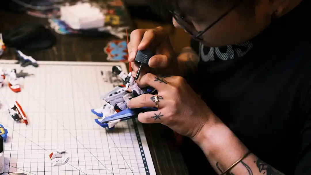 男性が机の上でガンプラのパーツを組み立てている様子