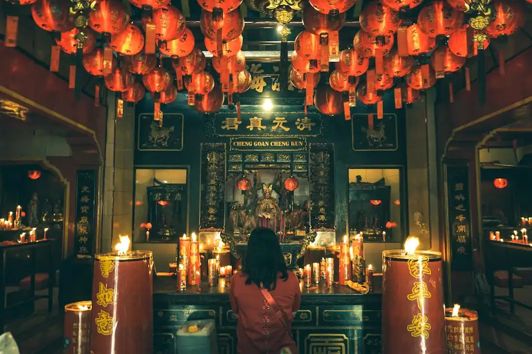 一位穿著紅色傳統服飾的女子在寺廟中祈福。