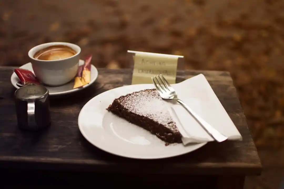 木のトレイに乗せられた、美味しそうなチョコレートケーキとカフェラテの俯瞰写真。