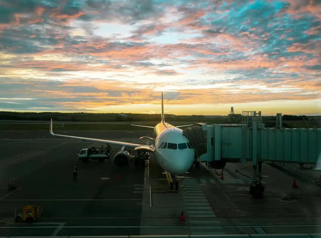 一架飛機停在澎湖馬公機場的停機坪上,背景是絢爛的夕陽彩霞。