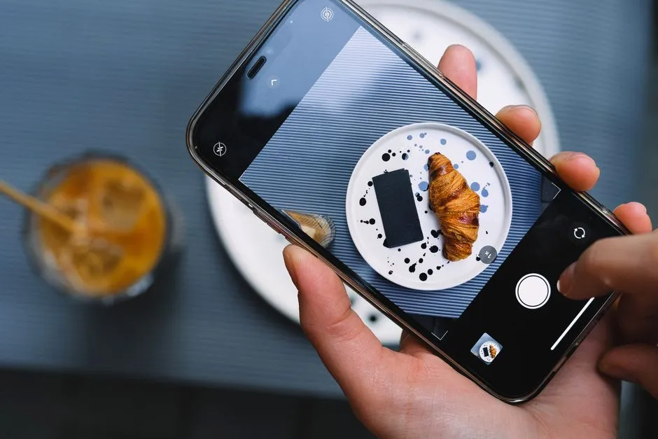 お洒落な皿に盛られたクロワッサンとコーヒーをスマートフォンで撮影している様子