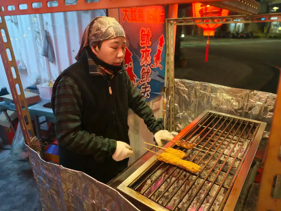 夜市攤販正在烤架上燒烤著一串串的食物。