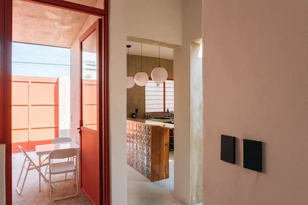 一間擁有戶外庭院景觀的現代廚房,中央有一個大理石中島,旁邊擺放著木製高腳椅。