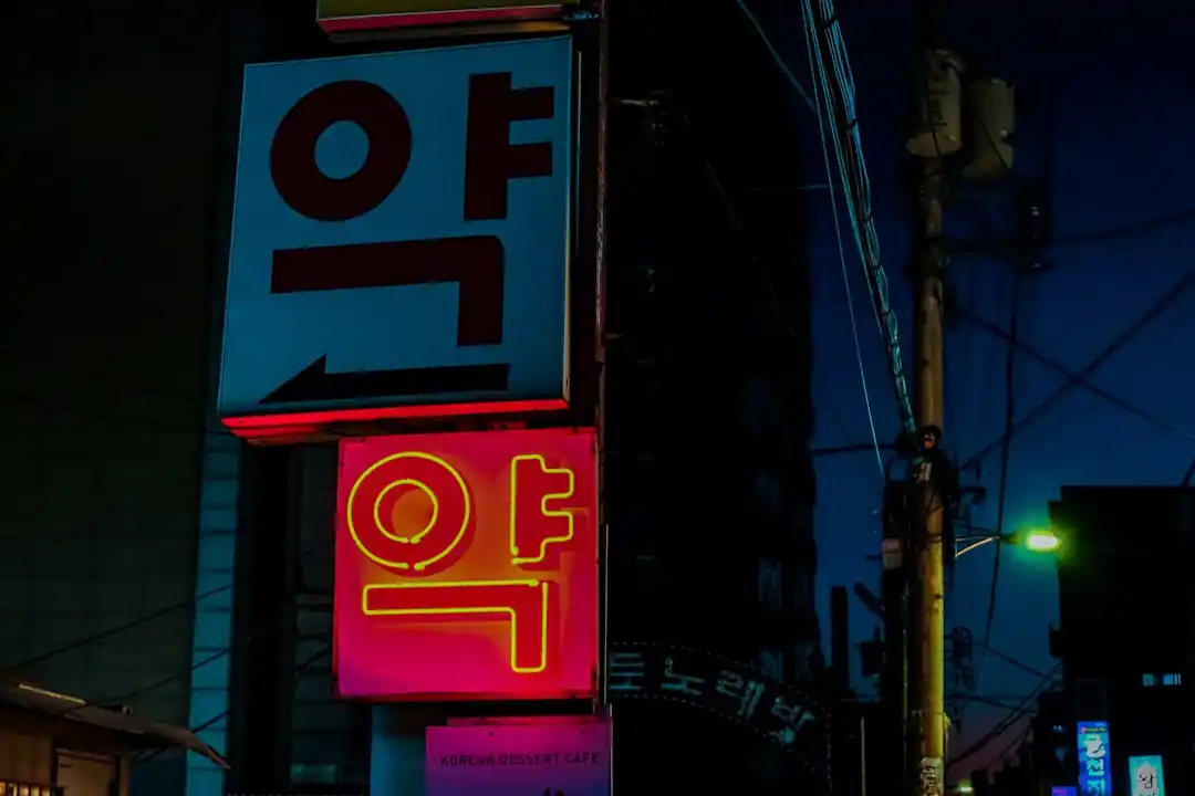 ネオンが光る夜の街角。「사랑」という韓国語のネオンサインが紫と白に輝いている。