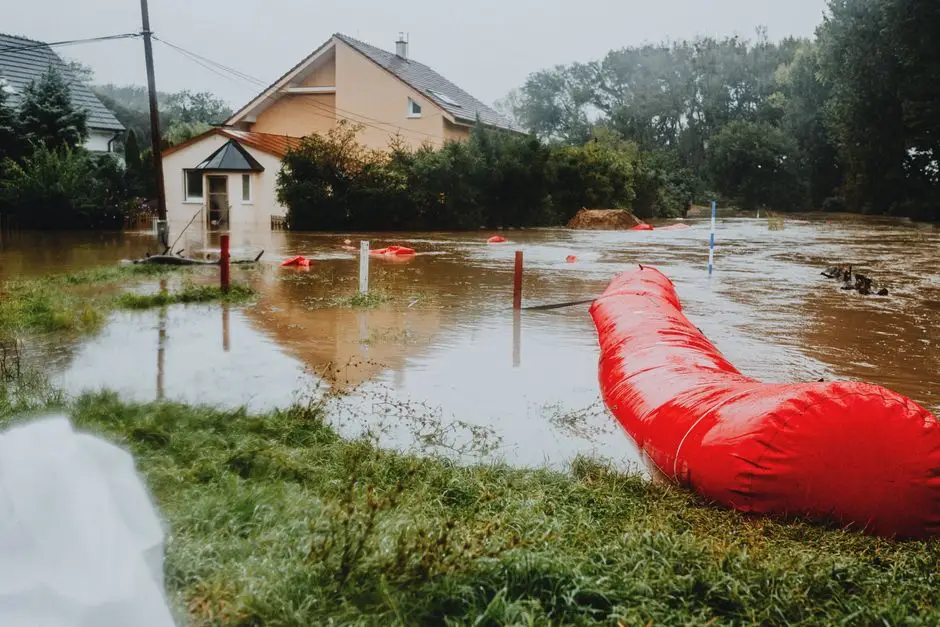 Flooded residential area protected by red flood barriers, showing severe weather impact.