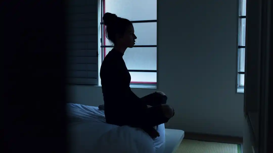 一位穿著舒適衣物的女性,在床上盤腿而坐,神情放鬆。