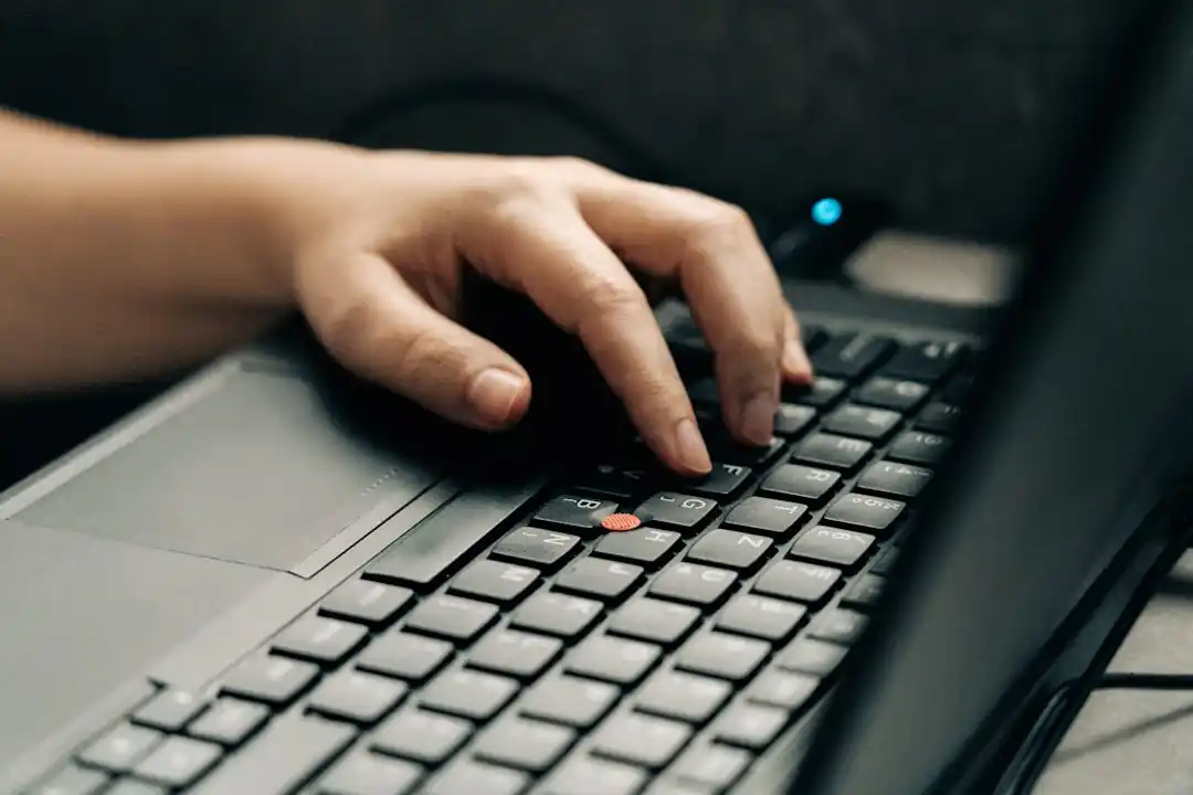自宅の机でノートパソコンのキーボードを打つ男性