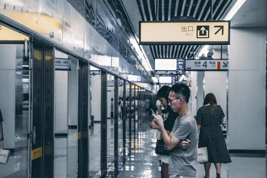 重慶の地下鉄駅のホームでスマートフォンを見ている男性
