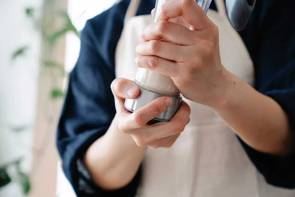 A person in an apron shaking a protein shaker bottle.
