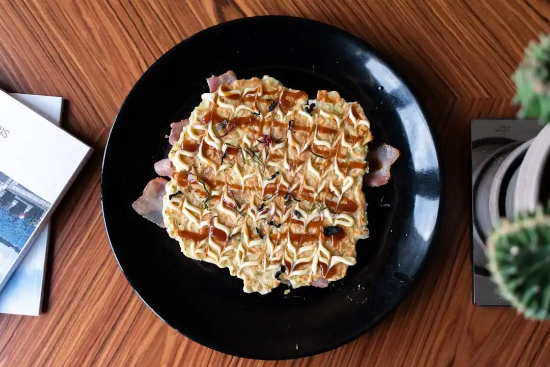 鉄板の上で焼かれ、ソースとマヨネーズがかけられたお好み焼き