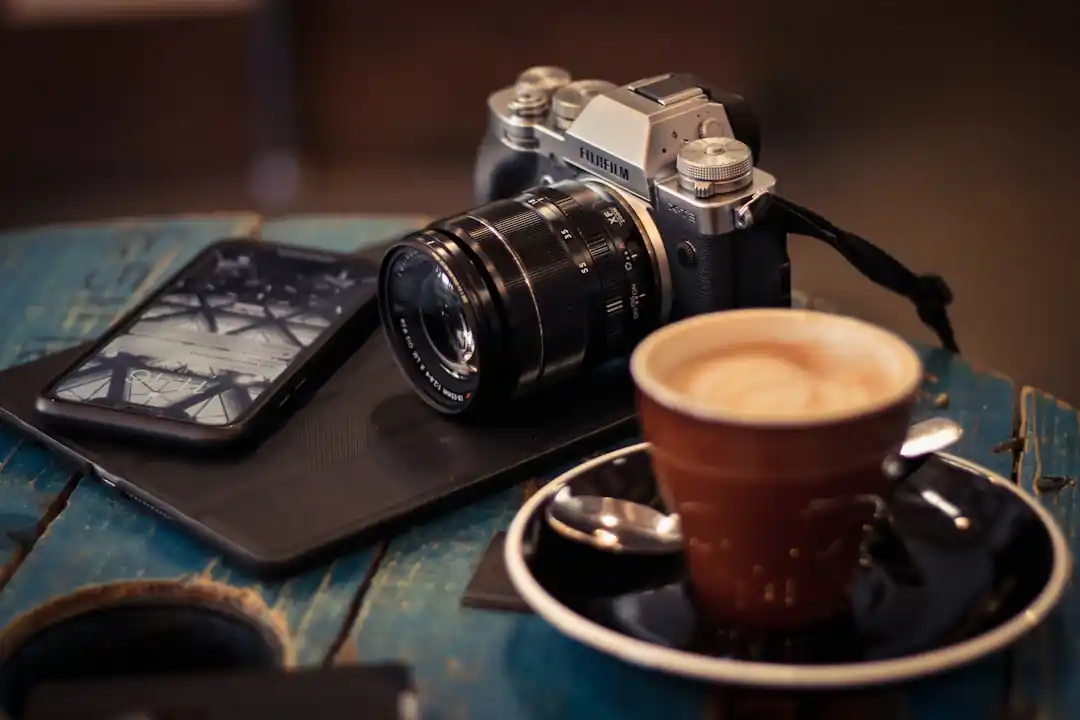 テーブルの上に置かれたインスタントカメラとコーヒーカップのフラットレイ写真