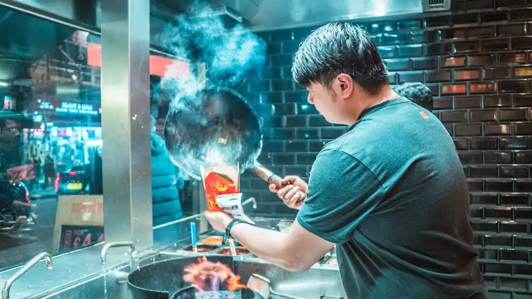 한 셰프가 나무 도마 위에서 칼을 들고 요리에 집중하고 있다.