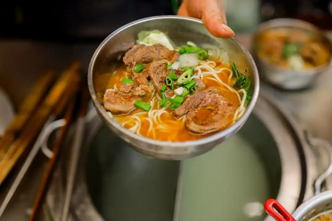 一碗熱氣騰騰的台式牛肉麵,麵條上鋪著鮮嫩的牛肉和青菜。