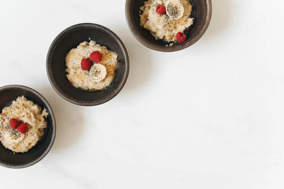 A warm bowl of oatmeal garnished with fresh raspberries, sliced banana, and sprinkled chia seeds.