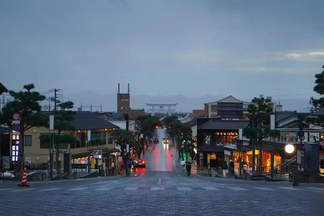 夕暮れ時、雨に濡れた出雲大社の参道。遠くに鳥居が見える。