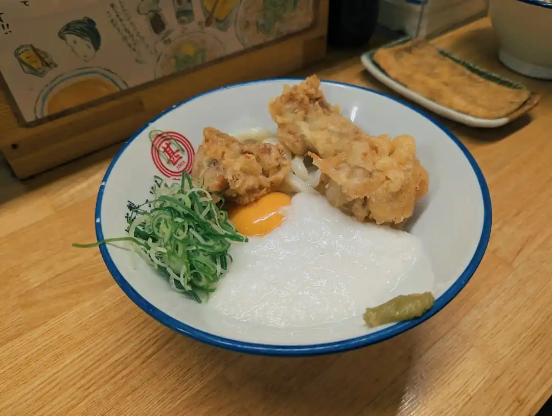 ご飯の上にフライドチキンと卵、ネギが乗っている