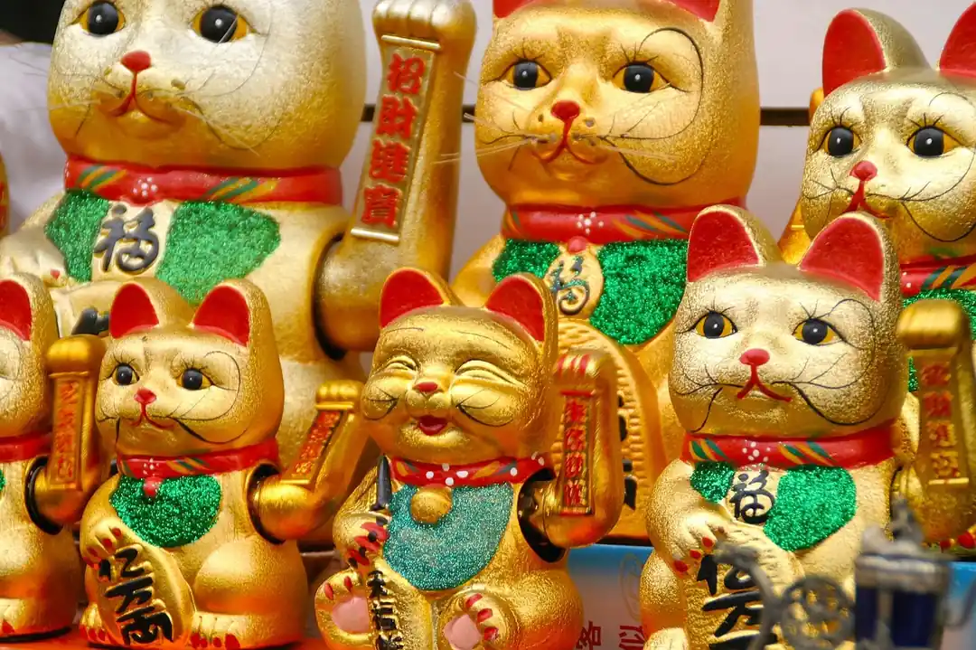 金色の背景に置かれた、右手を挙げている白い招き猫の置物。