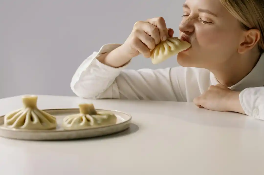 女性がジョージアの伝統料理ヒンカリを美味しそうに食べている様子。