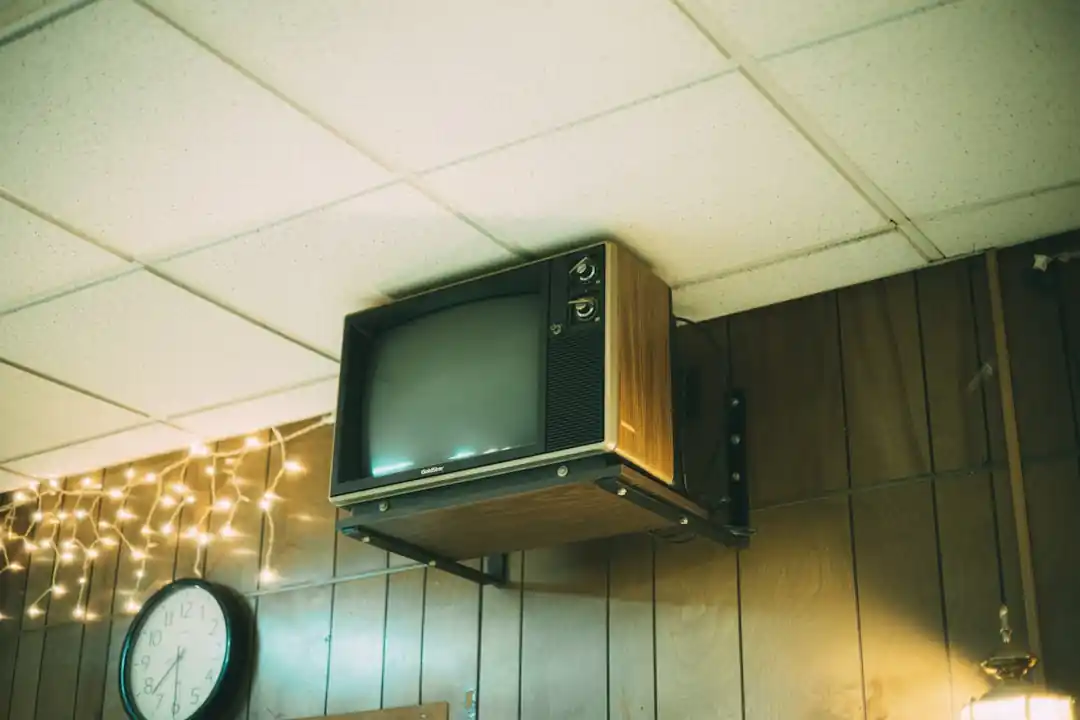 木製の棚の上に置かれたテレビと、その横にある白いケーブルボックス