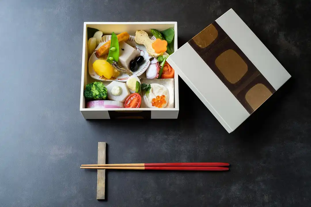 お重に美しく詰められたおせち料理。紅白なますや黒豆、海老などが彩りよく配置されている。