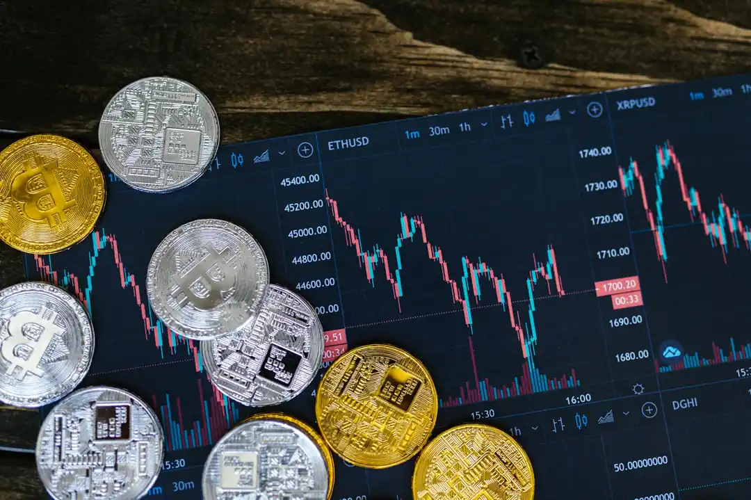 金銀兩色的加密貨幣實體幣與背景的數位交易圖表,象徵傳統貴金屬與現代金融的結合。