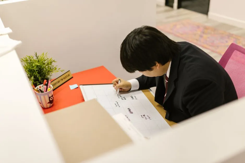 현대적인 사무실 책상에서 월간 달력에 일정을 기록하고 있는 직장인의 모습