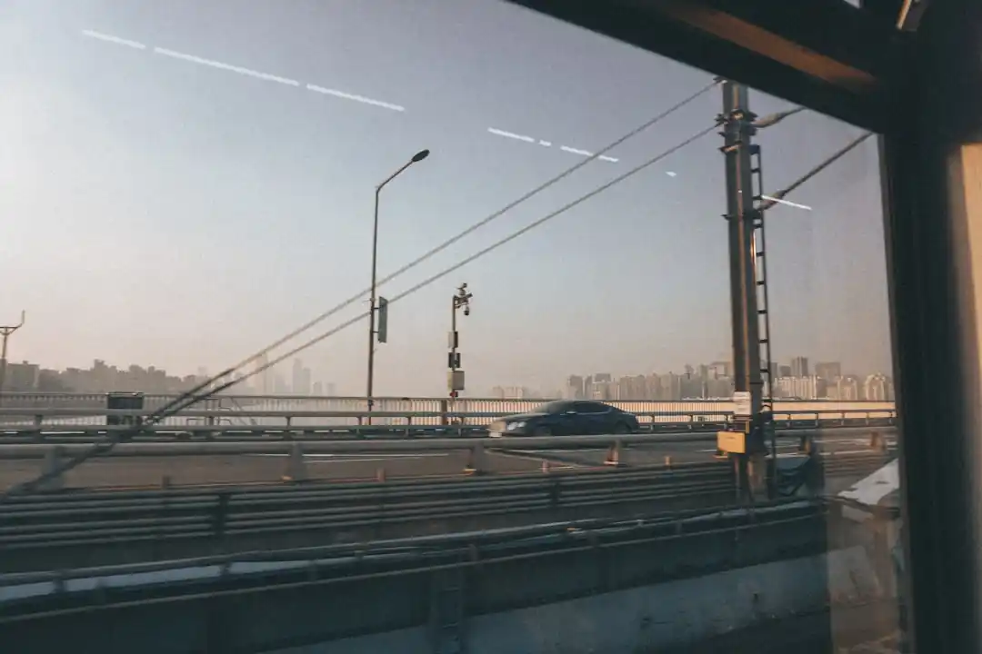 구름 낀 하늘 아래 산과 들을 배경으로 달리는 흑백 톤의 기차