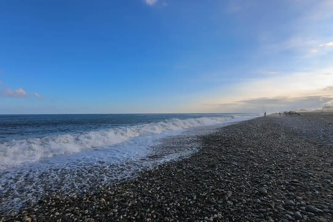 陽光灑在台東的海岸線上,沙灘與藍色海洋形成美麗的對比。