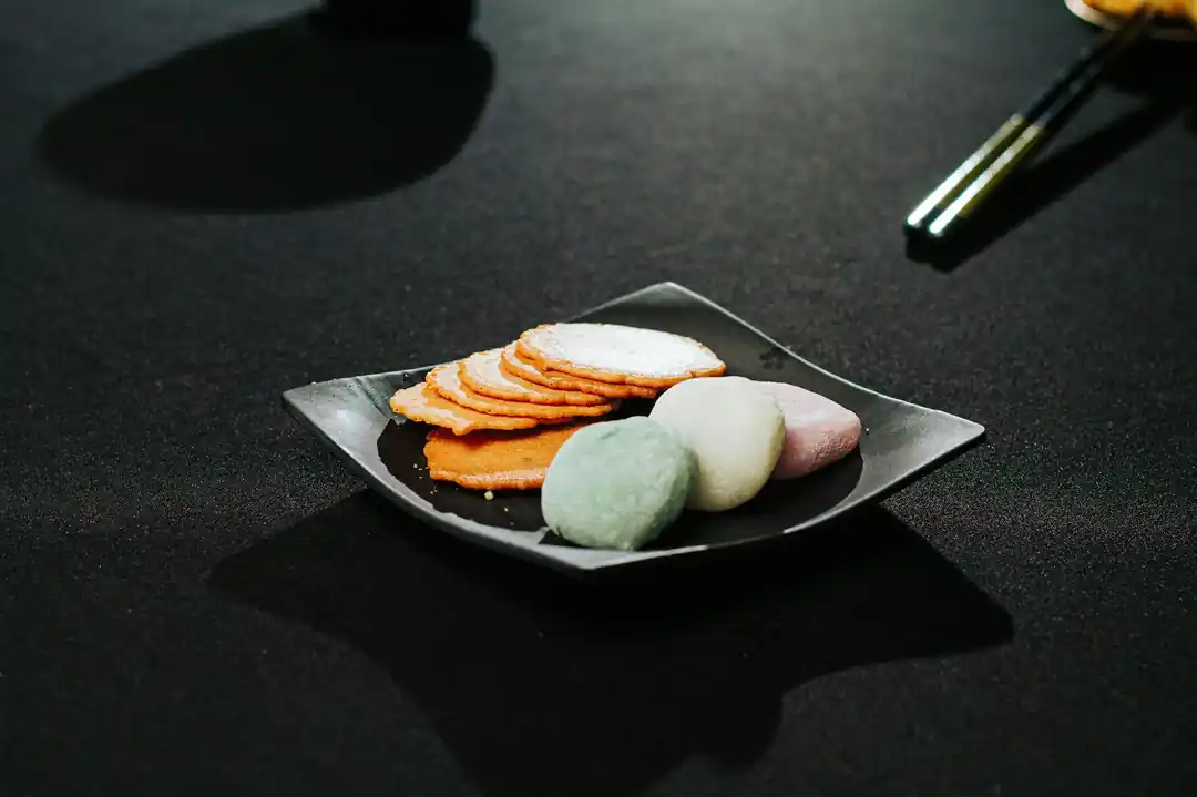 黒いお皿に盛り付けられた、色とりどりの餅菓子