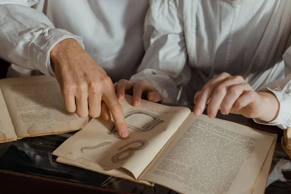 Two people examining detailed illustrations in a vintage book.