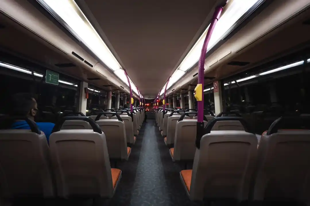 夜行バスの座席でブランケットにくるまり、窓の外を眺めながらリラックスしている女性