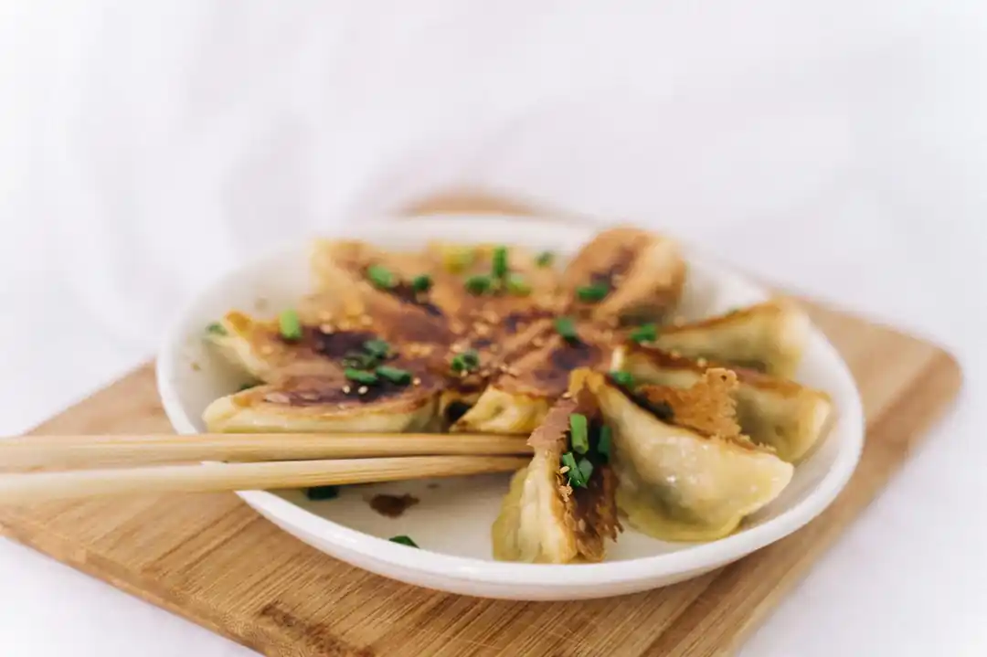 木の板に乗せられた焼き餃子と箸