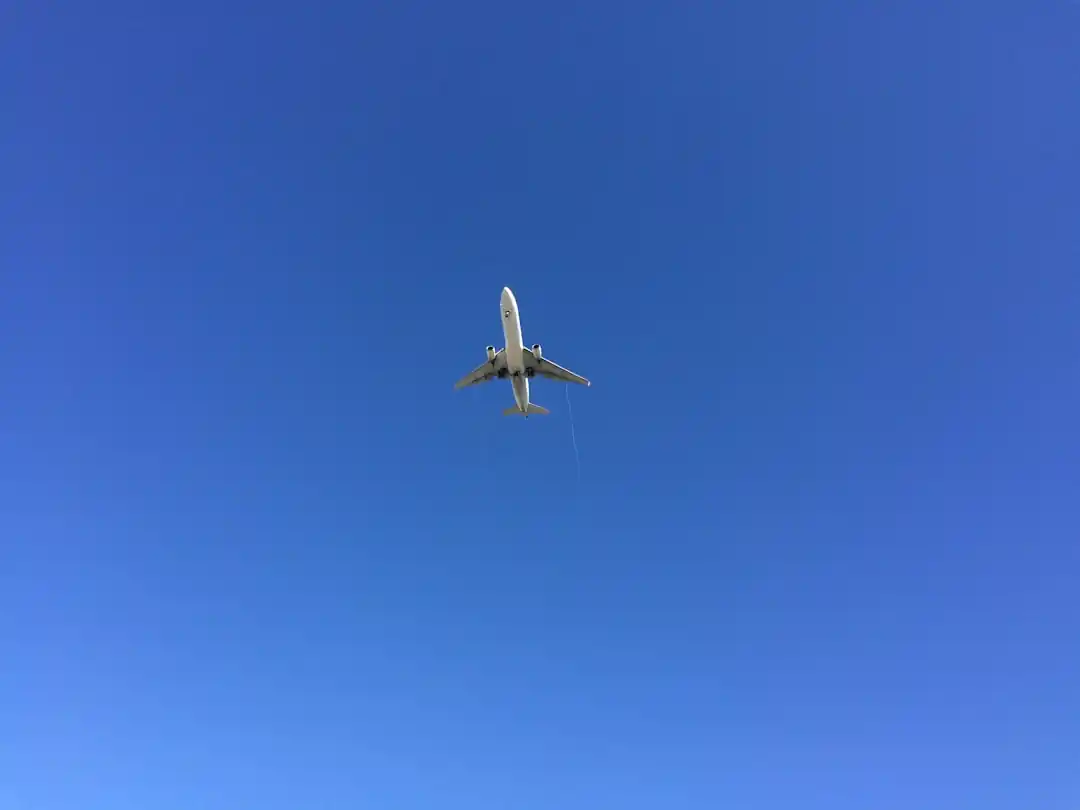 日中の空を飛ぶ白い飛行機