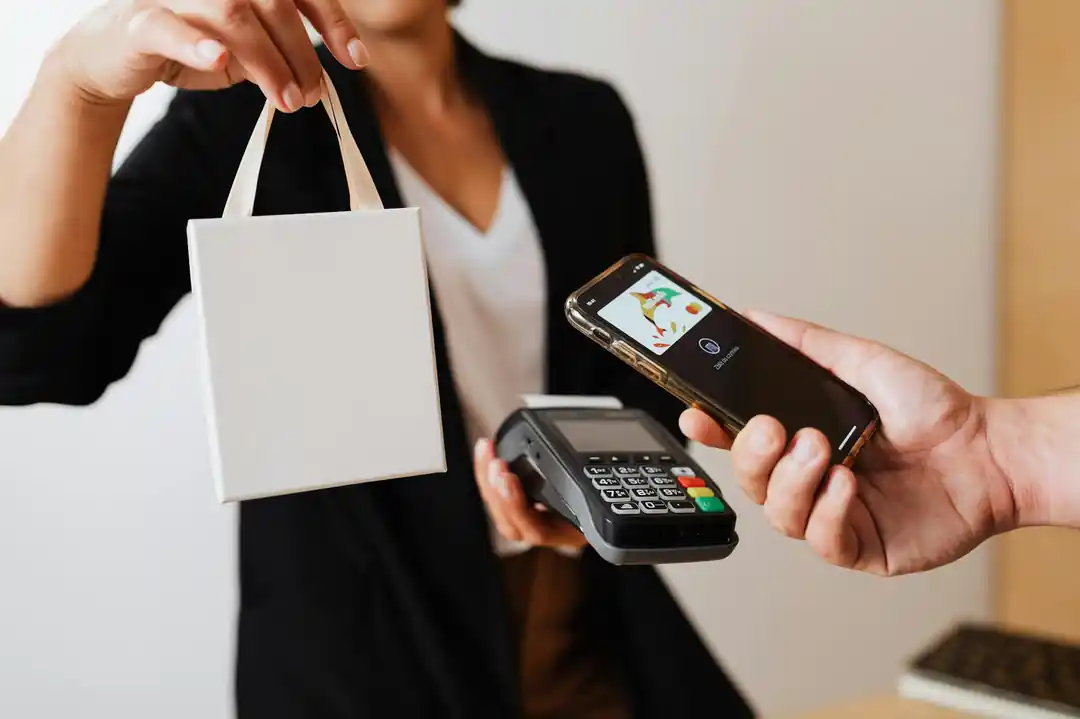 支払い端末でスマートフォンによる非接触決済を行いながら、ショッピングバッグを受け取っている様子