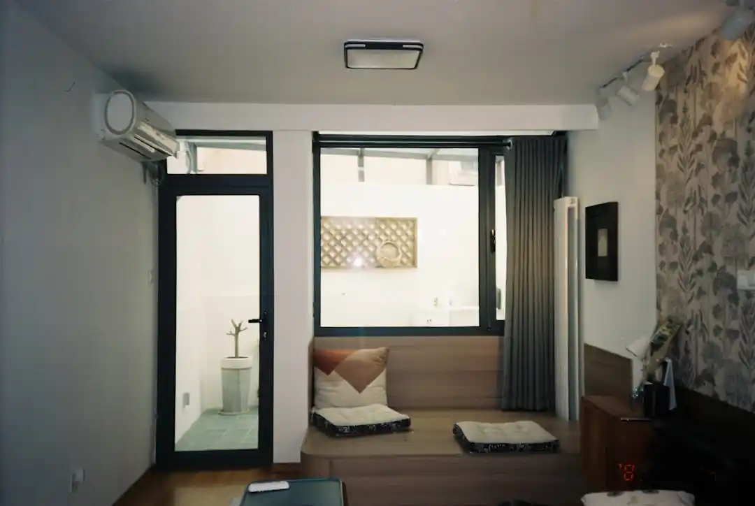 一個充滿自然光的舒適現代客廳,米色沙發旁有綠色植物,整體氛圍溫馨而寧靜。