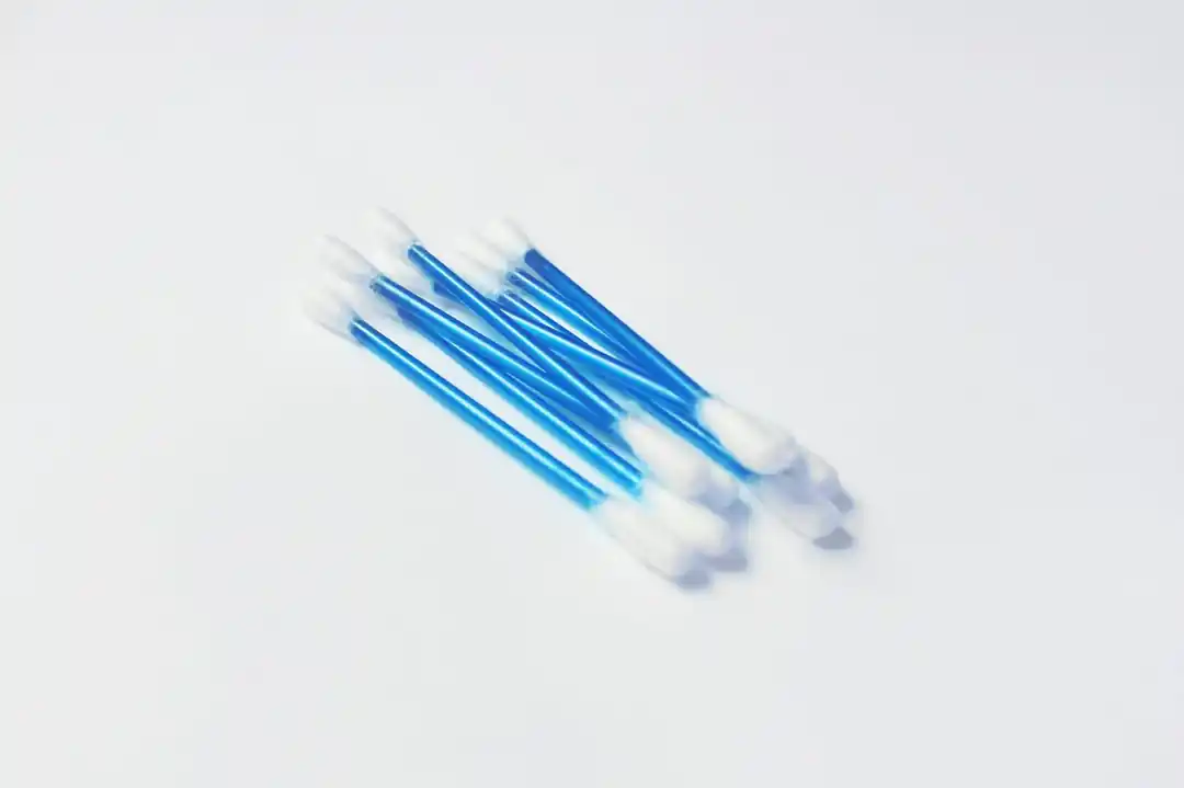 A close-up of several clean cotton swabs with blue handles on a white surface.