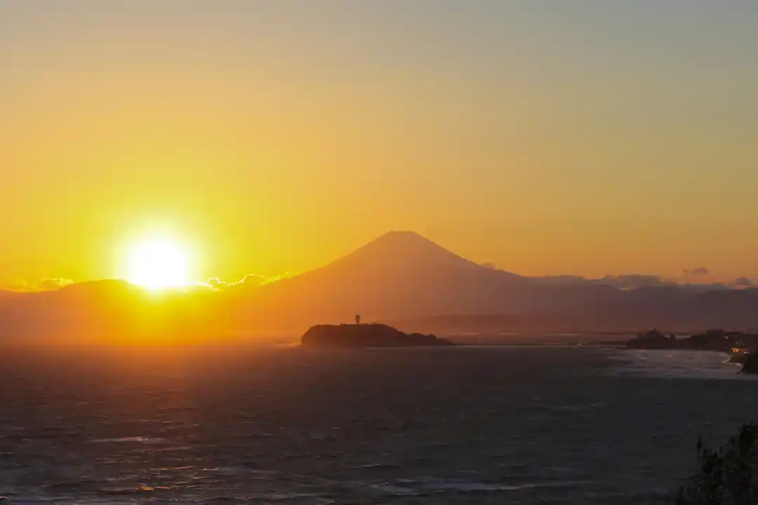 夕暮れの海に浮かぶ江の島と富士山のシルエット