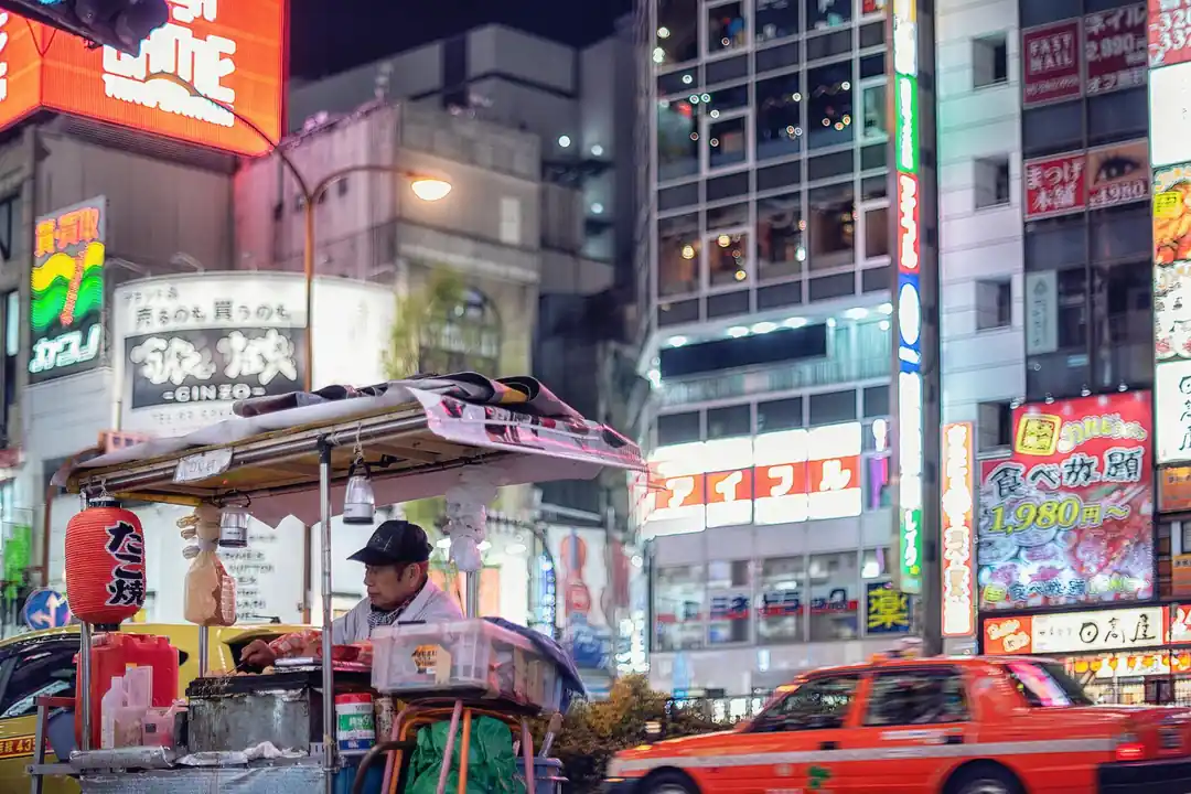 ネオンの下、屋台で調理をする料理人