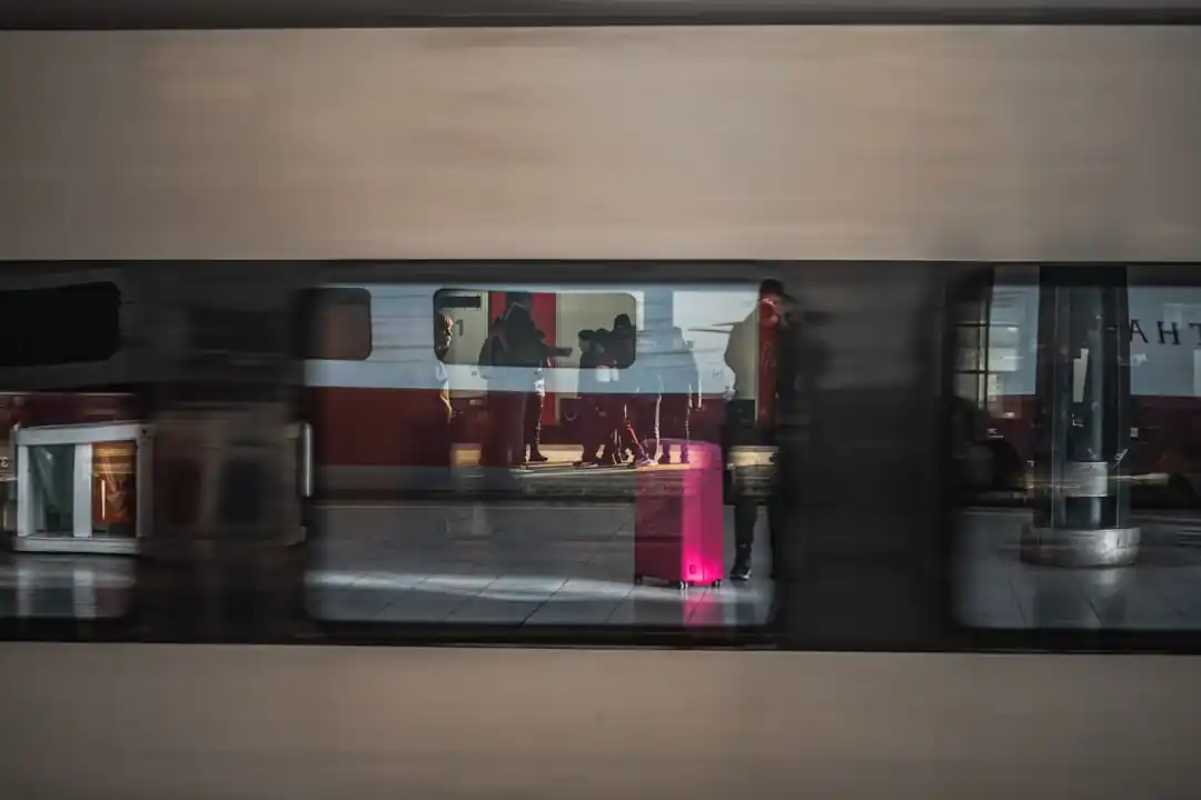 駅のプラットフォームを通過していく黄色と青の列車。