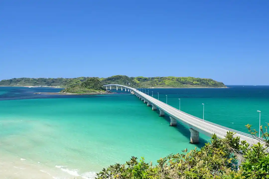 透き通ったエメラルドグリーンの海の上を、まっすぐに伸びる角島大橋の全景。