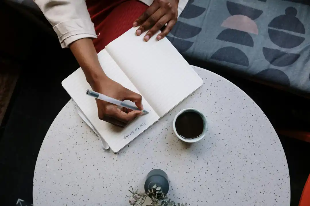 カフェの落ち着いた空間で、ノートに何かを書き込んでいる人の手元