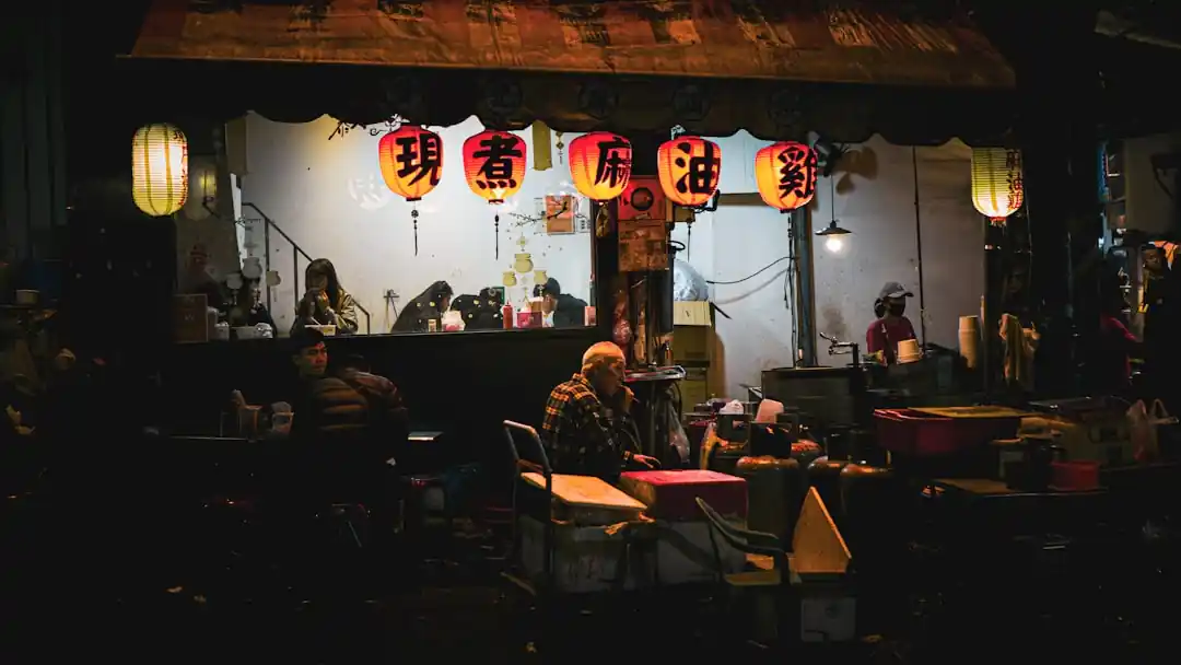 台中逢甲夜市裡,一個麻油雞小吃攤在夜晚亮著溫暖的紅色燈籠。